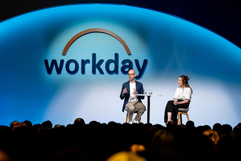 two figures in discussion on stage at a Workday conference